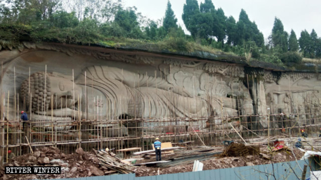 Gli operai al lavoro per coprire la statua del Buddha disteso nella zona panoramica del monte Lingyun