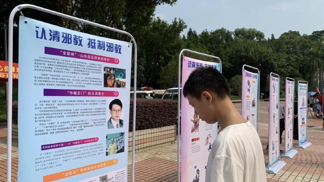 Un giovane visita una mostra di propaganda contro gli xie jiao organizzata in una comunità nella città di Guangzhou, nella provincia del Guangdong