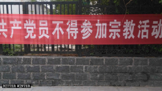 Uno striscione esposto in una strada di Shangbali, un borgo nella giurisdizione della città di Huixian nella provincia dell’Henan, proibisce ai membri del Partito di partecipare ad attività religiose