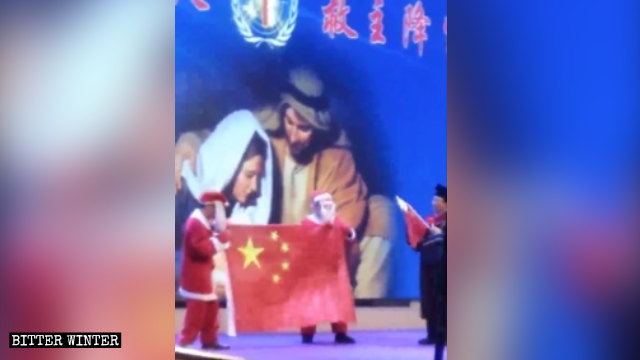 Un attore che recita la parte di Babbo Natale mostra la bandiera cinese durante la rappresentazione