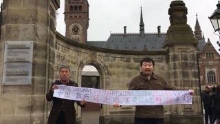 l’attivista cinese per i diritti umani Ma Yongtao (a destra) guida una manifestazione alla Corte Internazionale di Giustizia nella città neerlandese de L’Aia.