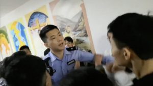 Un poliziotto tenta di arrestare uno studente mentre i funzionari governativi chiedono informazioni per l’identificazione dei presenti
