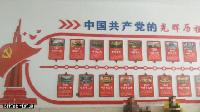 Un poster con le parole «Storia gloriosa del Partito Comunista» affisso sul muro della chiesa nel villaggio di Caowu