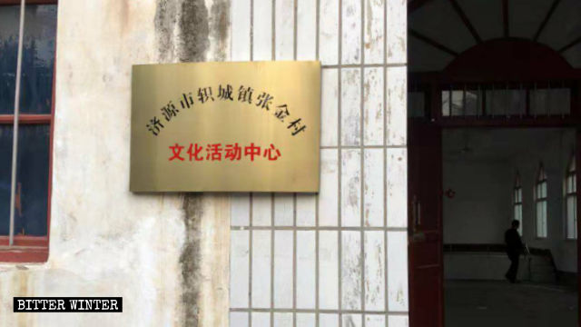 Un cartello con scritto «Centro per le attività culturali del villaggio di Zhangjin» sul muro della chiesa delle Tre Autonomie nel villaggio di Zhangjin