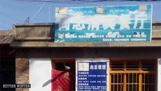 Tre nuovi segni fatti con vernice, nastro adesivo e altro appaiono sull'insegna di un ristorante etnico hui nella municipalità di Taipingdian della città di Baiyi, nella provincia del Gansu