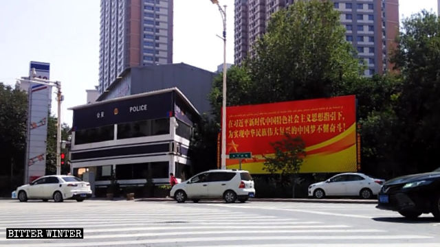 La stazione di polizia, telecamere di sorveglianza e un grande cartellone di propaganda a Urumqi