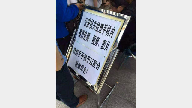 Un cartello di avvertimento in un posto di confine nello Xinjiang informa che i telefoni cellulari di tutti coloro che lo attraversano saranno controllati. 
