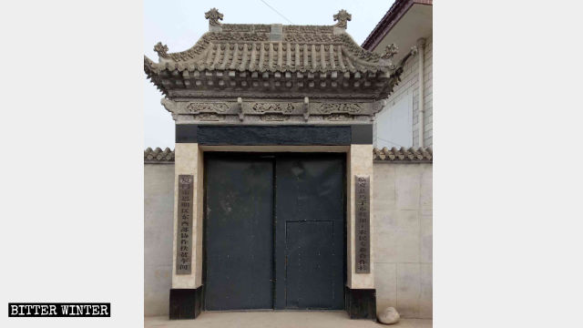 La porta della moschea sostituita con un comune cancello di ferro e le due nuove insegne indicanti che l'edificio non è più una moschea