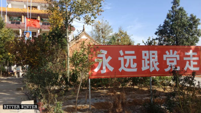 Un cartello con scritto «Segui il partito per sempre» di fronte al tempio Tianyi