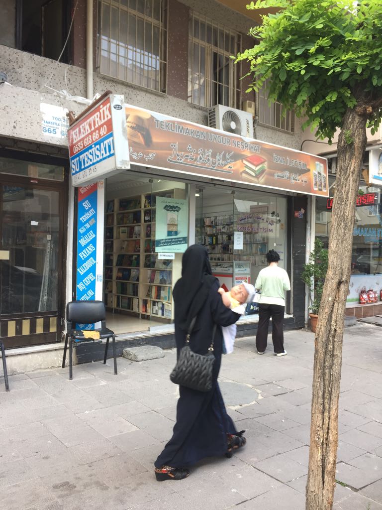 Una "vedova" uigura passa davanti a una libreria uigura a Istanbul