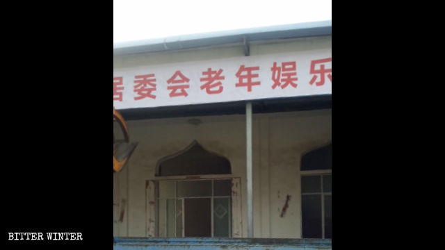 Cartello con scritto «Centro attività per anziani» appeso fuori dalla moschea
