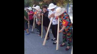 In una località dello Xinjiang, alcune persone con mazze di legno partecipano a “esercitazioni antiterrorismo”