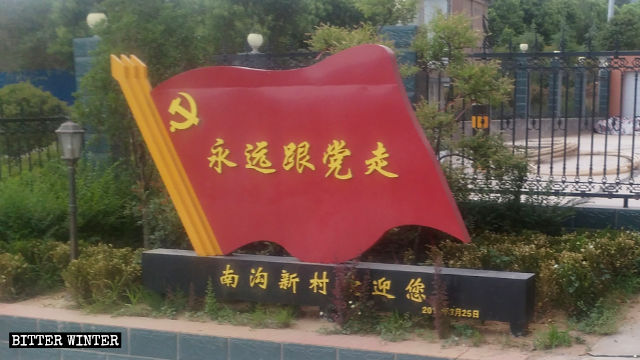 In una zona residenziale un cartello propagandistico a forma di bandiera dice: «Segui sempre il Partito»