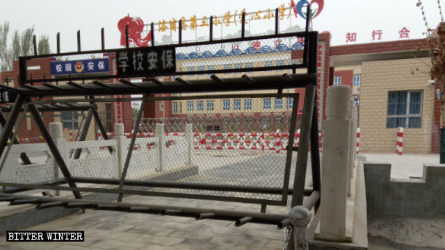Questa scuola elementare nella contea di Lop nello Xinjiang accoglie i bambini i cui genitori sono stati rinchiusi nei campi per la trasformazione attraverso l’educazione e il cancello è rigorosamente sorvegliato