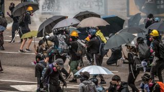 I manifestanti e i reporter di Hong Kong hanno bisogno di maschere e ombrelli per resistere agli attacchi con i gas lacrimogeni della polizia