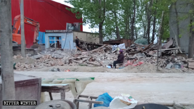 Un’anziana siede vicino alle rovine della sua casa distrutta nella città di Zhumadian