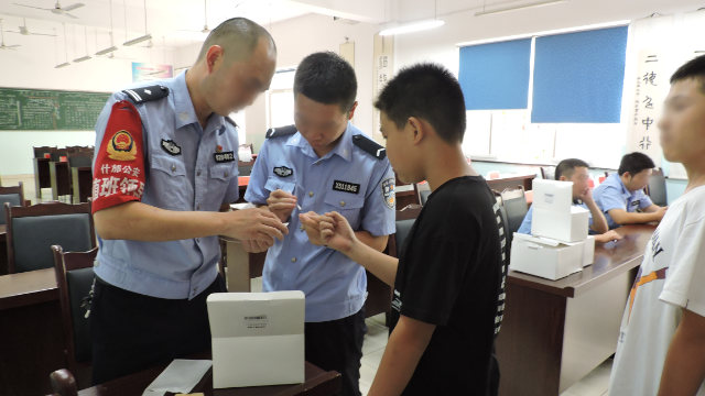 Agenti dell'Ufficio per la sicurezza pubblica della città di Shifang nel Sichuan raccolgono i campioni del DNA degli studenti delle scuole medie