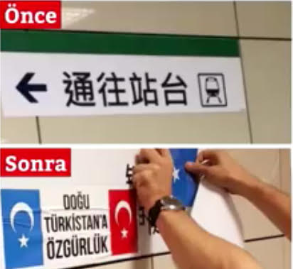 Sotto le istruzioni in lingua mandarina che conducono al binario del tram, un simpatizzante turco attacca le bandiere del Turkestan orientale e della Turchia