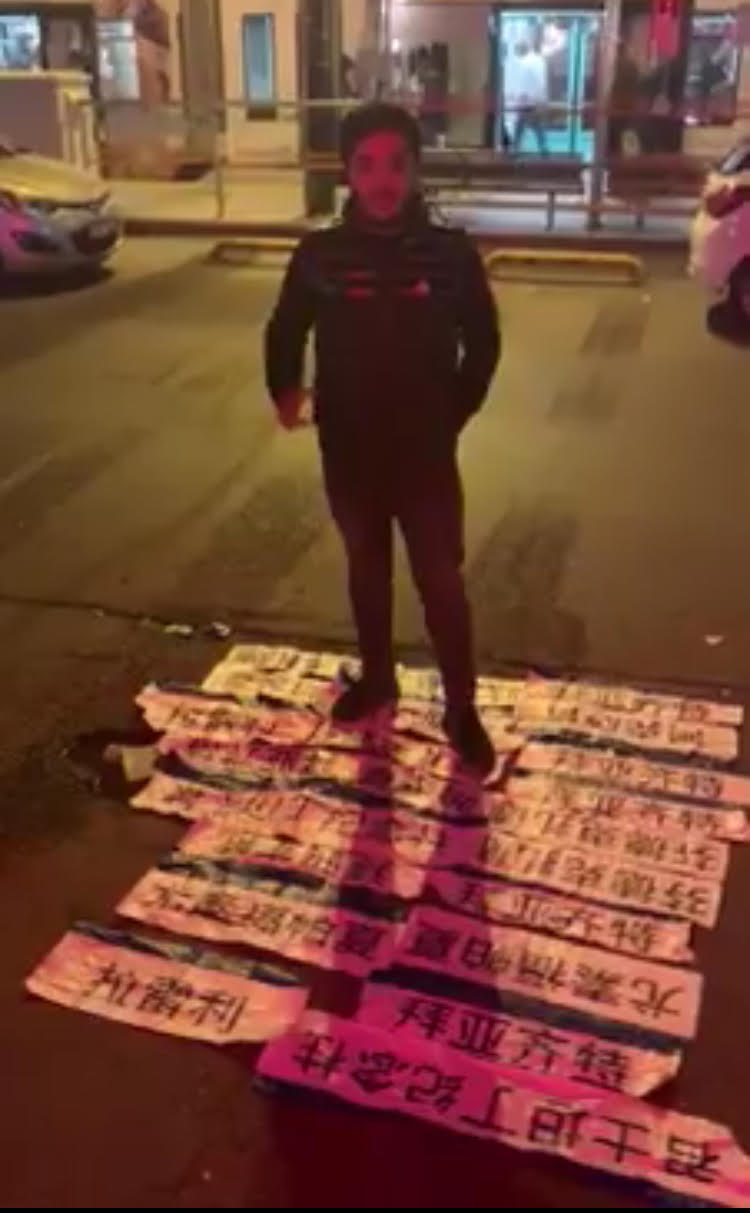 Un giovane uiguro in piedi davanti a tutti i cartelli delle fermate della linea tramviaria, scritti in mandarino, che insieme al suo gruppo di sostenitori turchi ha fatto in modo di rimuovere nel giro di una sola notte
