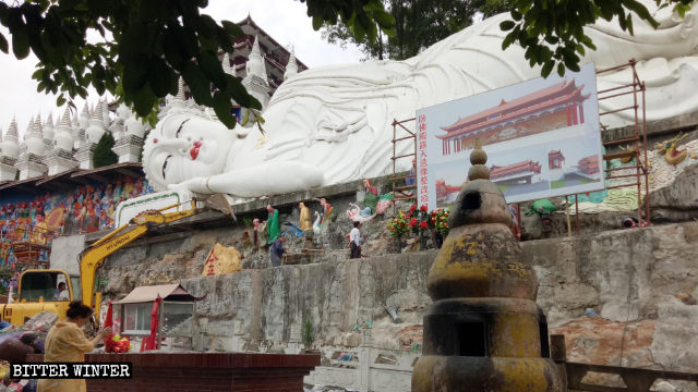 Un escavatore durante la demolizione delle 500 statue degli Arhat attorno al Buddha disteso