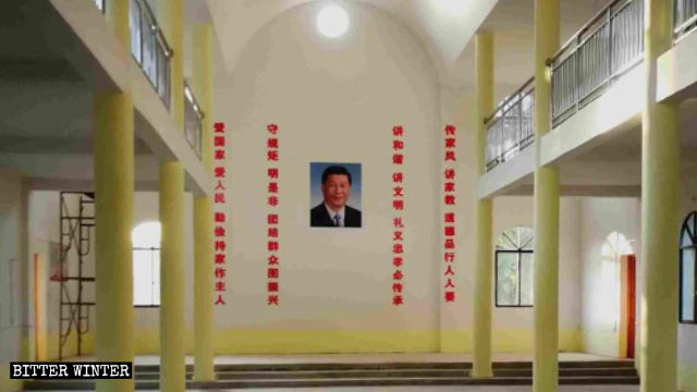 Il ritratto del presidente Xi Jinping appeso al centro della parete della chiesa, con slogan di propaganda a entrambi i lati