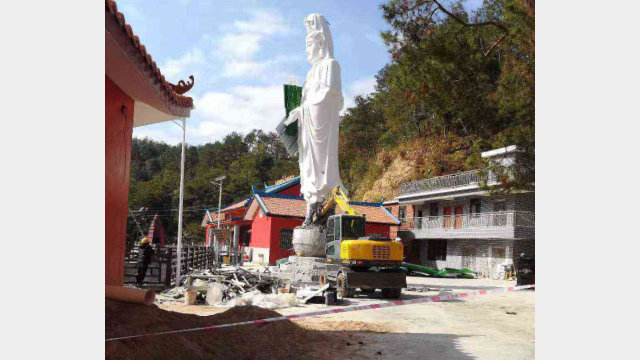 Operai demoliscono la statua della Guanyin